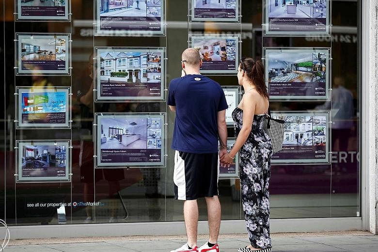 A couple viewing advertisements of properties for sale in an estate agency's window in London. Mayor Sadiq Khan has announced the launch of an unprecedented inquiry into foreign home ownership and "dirty money" that is allegedly being used to buy pro