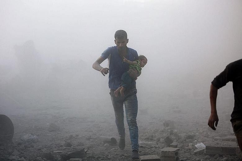 A Syrian man with a child fleeing from a reported air strike on a rebel-held area near Damascus.