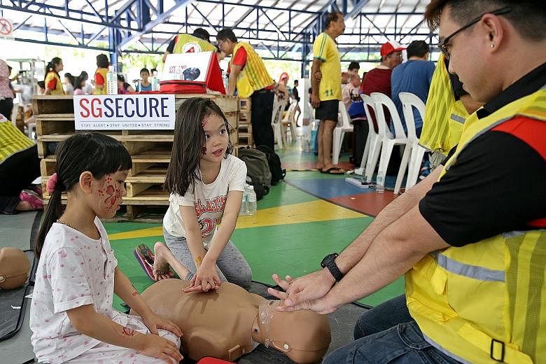 Sisters Quek Gek Ling (left), six, and Gek Boon, eight, learning about CPR from Community Emergency Response Team member Adris Chong at a Hougang block in July. There is greater awareness of the benefits of being trained in CPR, and more schools, com