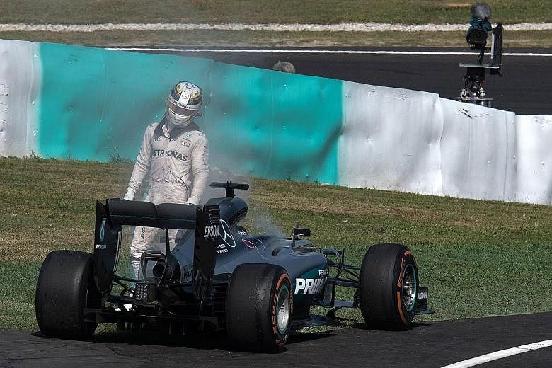 Lewis Hamilton leaving his car after flames appeared at the back of his Mercedes following engine failure during the Malaysia Grand Prix.