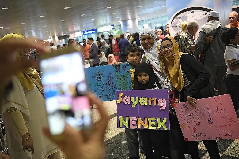 Three siblings turned up at Changi Airport yesterday to greet their grandmother, housewife Azizah Sawal (in white tudung), who was returning from the haj in Mecca. Yesterday was her 57th birthday, and her grandchildren (from left) Hadi Danial, nine, 