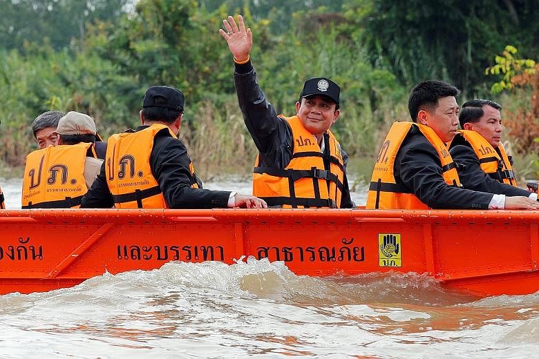 Thailand's Prime Minister Prayuth Chan-o-cha waves to flood-affected residents during his visit to Sena district in the ancient city of Ayutthaya yesterday. Floods in the past few weeks, and an overflow of water from the Chao Phraya river, have inund