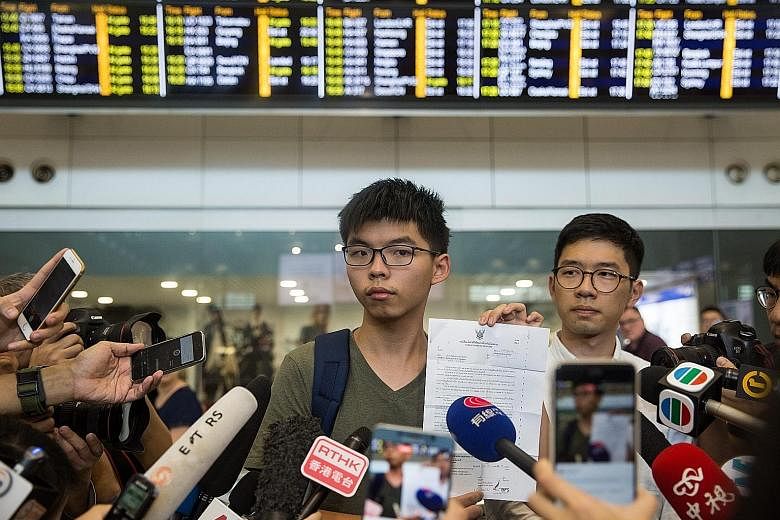 Mr Wong showing Thai immigration documents as Mr Nathan Law, lawmaker-elect and chairman of Demosisto, looked on during a press conference at Hong Kong International Airport yesterday. The 19-year-old protested against the "illegal detention".
