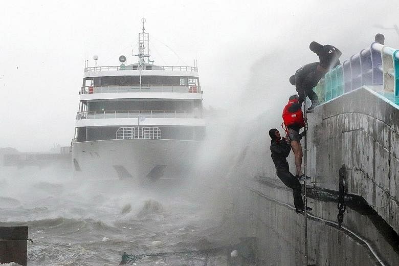 South Korean coast guard personnel rescuing crew members of a stranded passenger ship in the aftermath of Typhoon Chaba in the southern city of Yeosu yesterday. Chaba has killed at least four people as it bulldozed through southern parts of South Kor