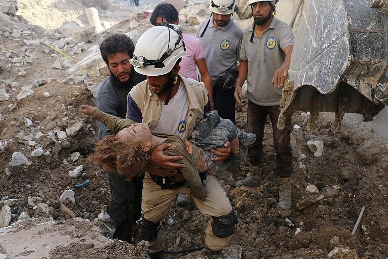 A Syrian civil defence volunteer, from the group known as the White Helmets, holds the body of a child pulled from the rubble following an air strike by government forces on the rebel-held neighbourhood of Karm Homad in the northern city of Aleppo on