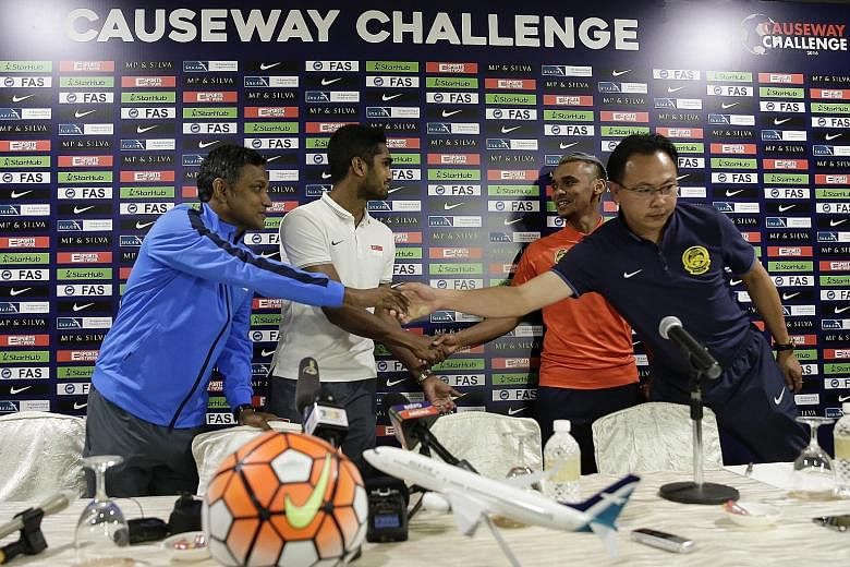 Lions coach V. Sundramoorthy (left) and captain Hariss Harun extend greetings to Malaysian counterparts Ong Kim Swee and Amri Yahyah.