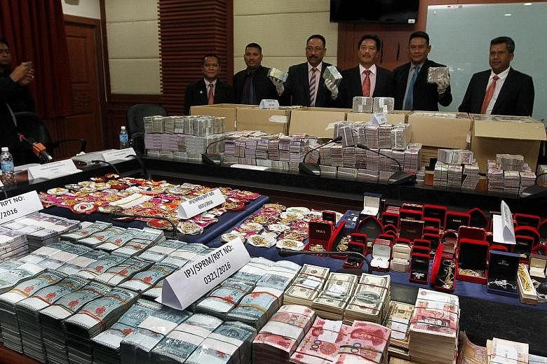 Datuk Azam (third from right) and other officers showing cash and jewellery seized from the top two officials of the Sabah Water Department in Kota Kinabalu on Wednesday.