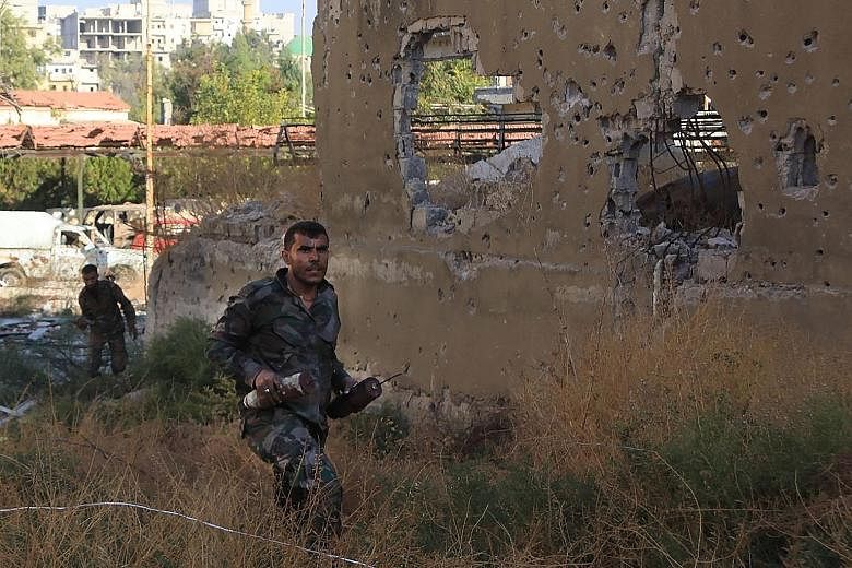 A Syrian pro- government soldier carrying homemade bombs in Aleppo's rebel-held Bustan al-Basha area yesterday.