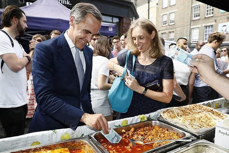 Mr Carney testing a new polymer £5 note by dipping it into a tray of food at a market stall last month. The British central bank governor has less than 90 days before a self-imposed deadline to declare a desire to serve his full eight-year term thro