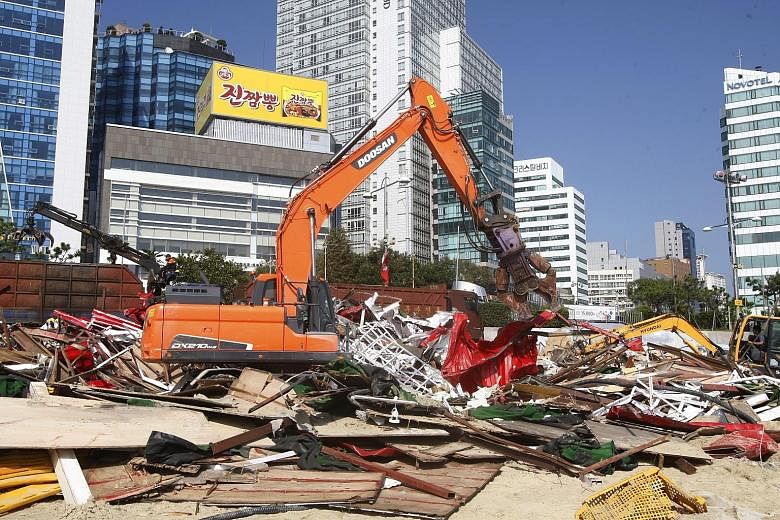 Debris from structures erected on Haeundae beach, the venue for the Busan International Film Festival, being cleared away yesterday. Festival events had to be cancelled or moved indoors.