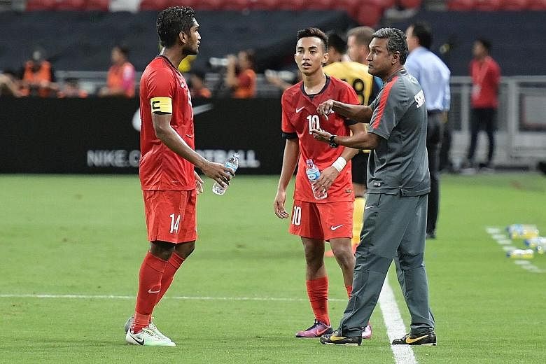 Singapore caretaker coach V. Sundramoorthy passing instructions to captain Hariss Harun and Faris Ramli during a break in last night's game.