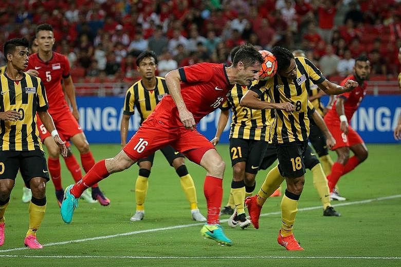 Singapore defender Daniel Bennett (No. 16) and Malaysia forward Hazwan Bakri (No. 18) challenge for the ball during the stalemate at the National Stadium.