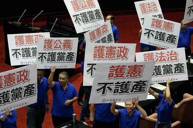 KMT lawmakers with placards that read "Protect the Constitution, not the party assets", inside Taipei's Parliament in July. The current probe into whether the KMT had inappropriately amassed its assets is part of the transitional justice that Preside