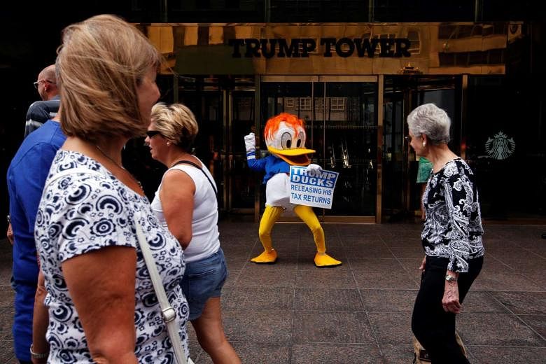 An activist with a sign referring to US presidential candidate Donald Trump and his tax returns outside Trump Tower in New York City last month. Based on the few pages of Mr Trump's 1995 tax returns that have become public, the writers have concluded that