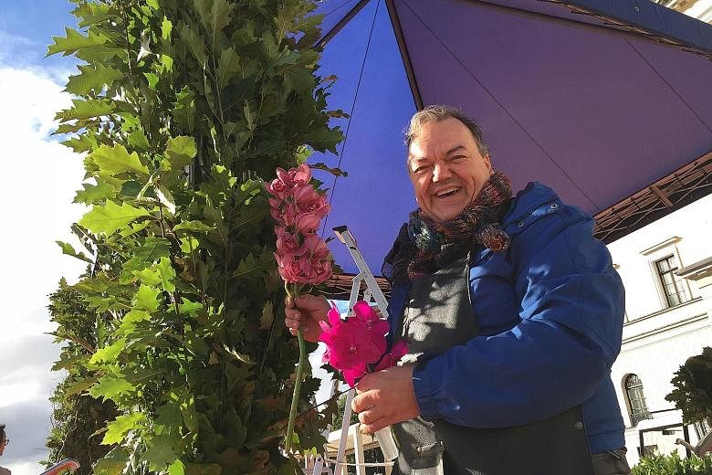 Florist Nils Norman Ivrsen decorating a stage with orchids. The stage is being set up in front of the Royal Palace where King Harald V and Queen Sonja will welcome President Tan.