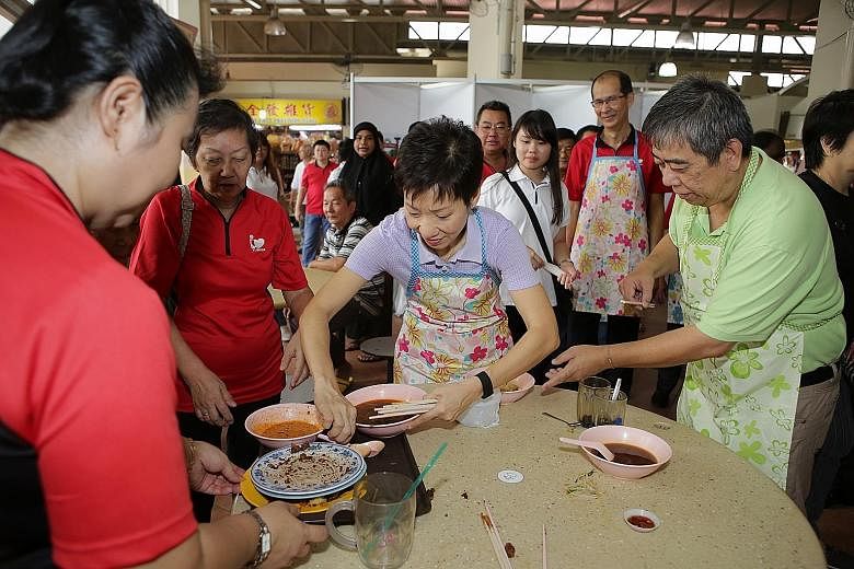 Minister for Culture, Community and Youth Grace Fu lending a hand with cleaning up at Yuhua Village Market and Food Centre as part of an outreach programme to encourage diners to return their trays after meals.