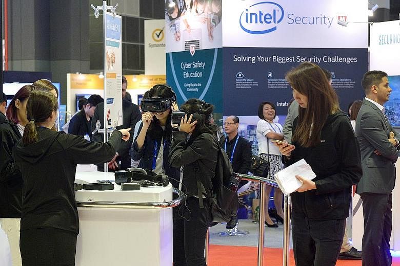 Visitors trying out virtual reality goggles at a booth at the inaugural Singapore International Cyber Week at Suntec Convention and Exhibition Centre yesterday.