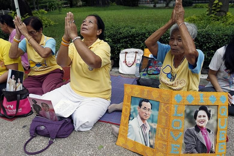 Well-wishers gather outside Siriraj Hospital in Bangkok yesterday with portraits of King Bhumibol Adulyadej and his wife Queen Sirikit to pray for the monarch's health.