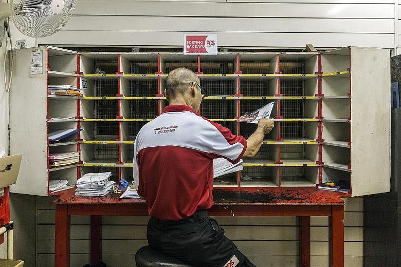A Pos Malaysia employee sorting mail in a post office in Kuala Lumpur. Increased parcel deliveries due to online shopping drove a 40 per cent jump in the company's profit in the fiscal first quarter.