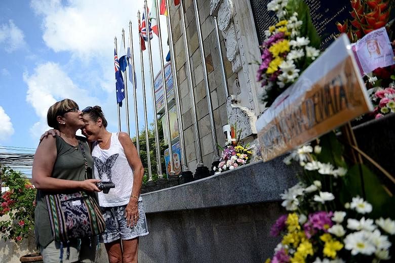 Mourners visiting the memorial for victims of the 2002 Bali bombings on the 14th anniversary of the blasts in the tourist district of Kuta near Denpasar, on the Indonesian resort island of Bali, yesterday. The blasts, blamed on the militant Jemaah Is
