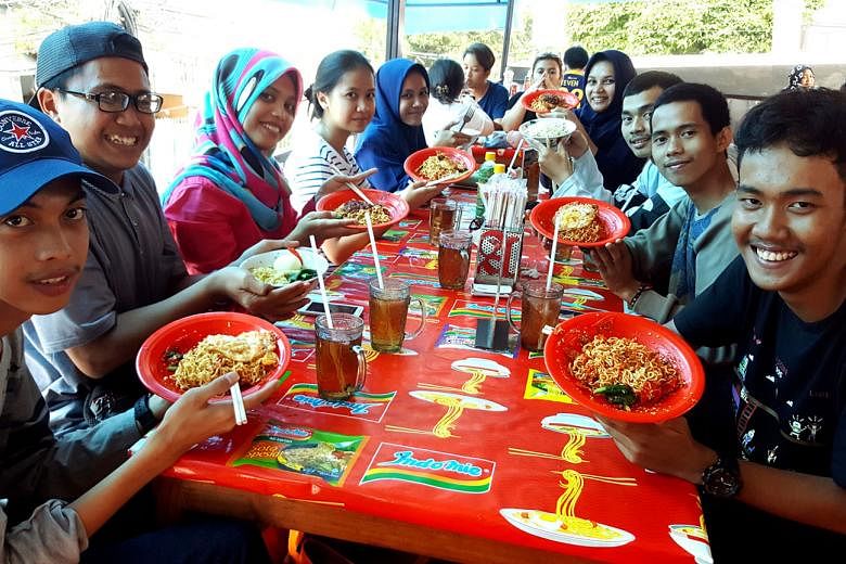 College students enjoying instant noodles at Warung Abang Adek, an eatery in Jakarta well known for its spicy renditions of the humble dish, including the Indomie Goreng Pedas Mampus which uses 100 chillies in a serving. 