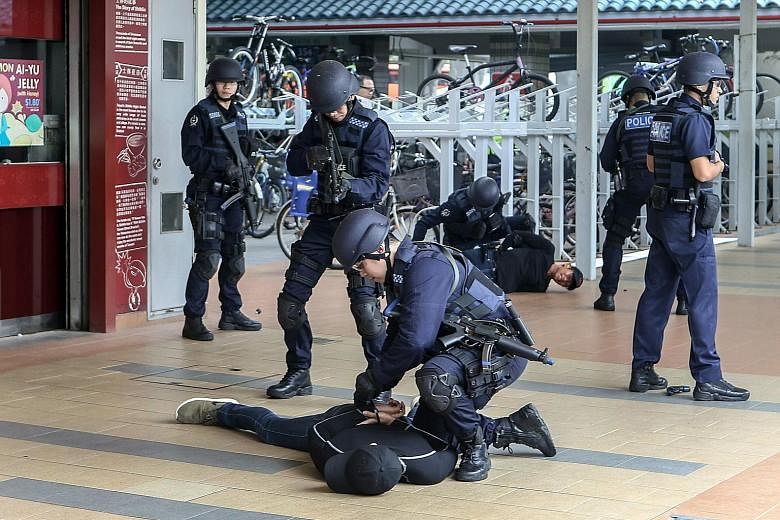 Above: The Emergency Response Team in action during a simulation of an attack by a gunman during the Pasir Ris West Emergency Preparedness event beside Pasir Ris MRT station yesterday. Left: In an actual emergency, telco users nearby will receive an 
