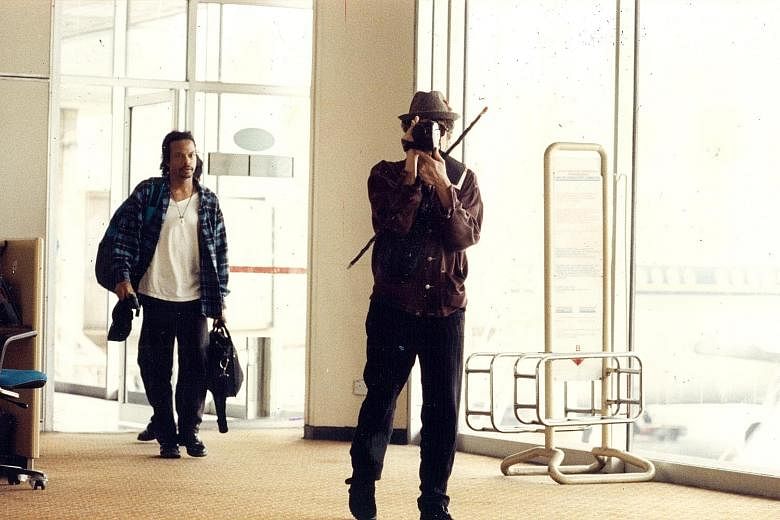 The notoriously private American songwriter and singer Bob Dylan (at right) hiding behind a video camera when The New Paper tried to photograph him at Kuala Lumpur International Airport on Feb 22, 1994. Behind him is one of his band members. Despite 