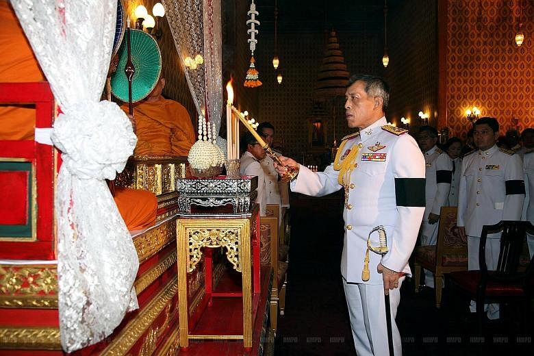 Thai Crown Prince Maha Vajiralongkorn lighting a candle in a ceremony honouring King Bhumibol at the Grand Palace in Bangkok on Saturday. A mourner praying as others queued to pay respects to King Bhumibol at the Grand Palace yesterday. Some Thais ha