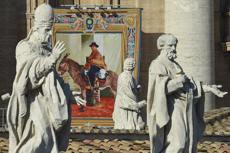 A tapestry portrait of new saint Jose Gabriel del Rosario Brochero hanging from the facade of St Peter's Basilica during a canonisation mass led by Pope Francis yesterday.
