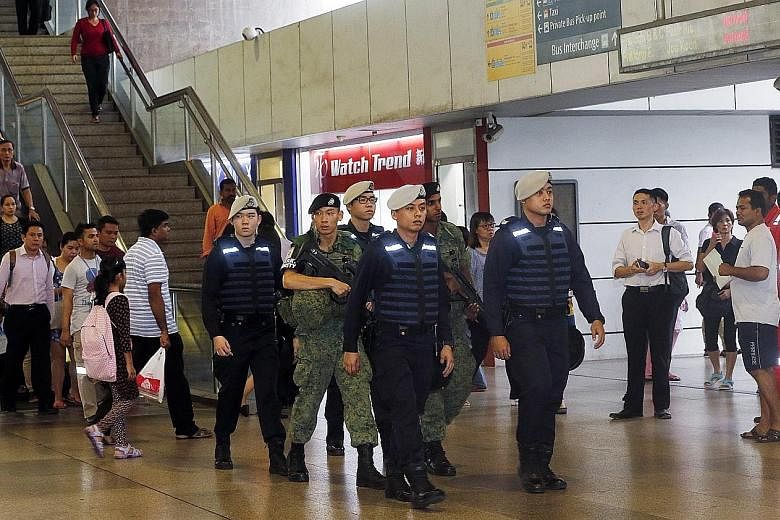 Public Transport Security Command police officers and SAF soldiers patrolling Jurong East MRT station during the evening peak hours yesterday. Security teams were deployed at various locations, including public transport hubs, shopping malls, residen