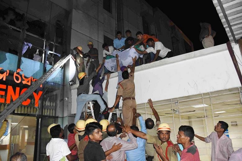 Rescue workers helping to move a patient after a fire broke out on Monday night in the ICU of SUM hospital in Bhubaneswar in India's eastern Odisha state.