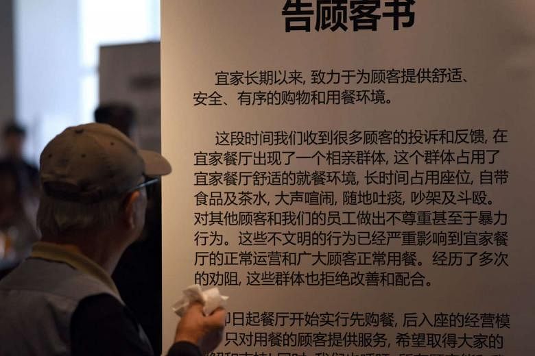 A man looking at a notice in Ikea Shanghai's restaurant. Its "no food, no seat" rule is to deter a group of older people looking for love from occupying its tables and socialising for many hours over free coffee. 