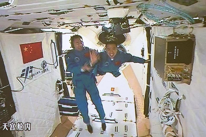 Chinese astronauts Jing Haipeng (left) and Chen Dong seen arriving at the Tiangong-2 space station yesterday in a live feed that was telecast on state television. This is Mr Jing's third space mission and Mr Chen's first. They will remain at the spac