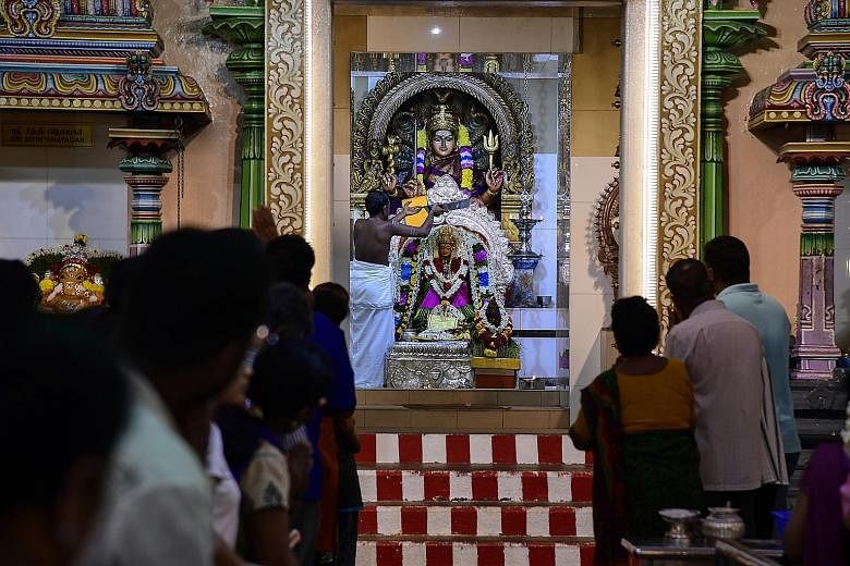 Devotees watch as a temple priest performs prayers. 