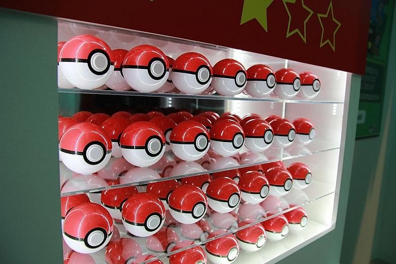 The giant Pokedex wall (left), an index of more than 700 of the characters with their names and images. Visitors can pick a red Pokeball (above) for an easy challenge.