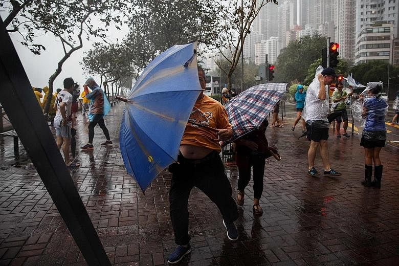 Pedestrians braving the storm yesterday morning when Hong Kong's storm signal was raised to No. 8, the third-highest level.