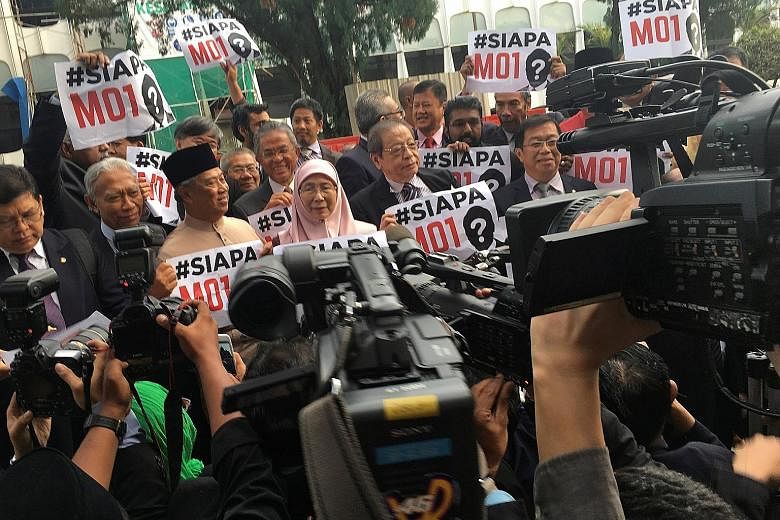 Malaysian opposition MPs holding up placards asking "Who is MO1 (Malaysian Official 1)?" after staging a walkout in protest in Parliament while Prime Minister Najib Razak was tabling the country's next Budget in Kuala Lumpur on Friday. Datuk Seri Naj