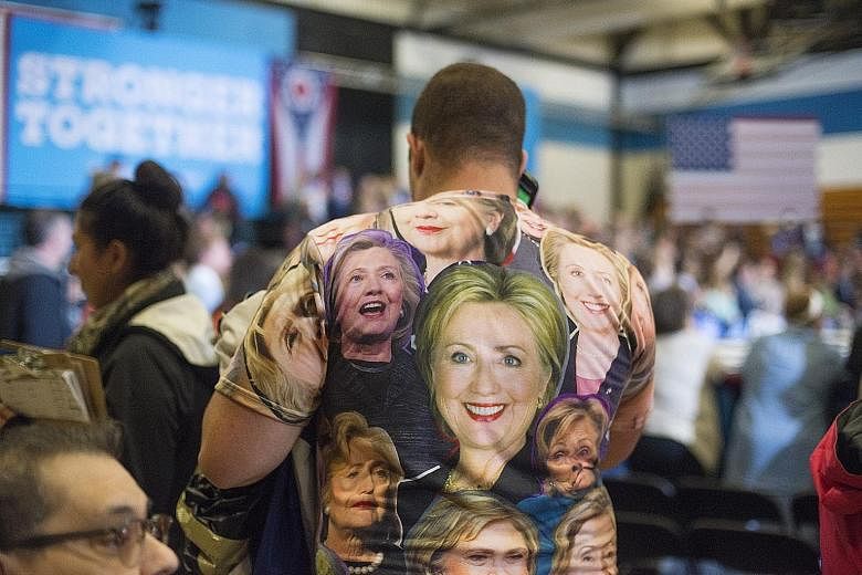 A Clinton supporter at a rally in Cleveland, Ohio, last Friday. Mrs Clinton and Mr Trump are currently tied in the battleground state, according to polls. Mrs Clinton at a campaign event with her running mate Tim Kaine in Philadelphia on Saturday.