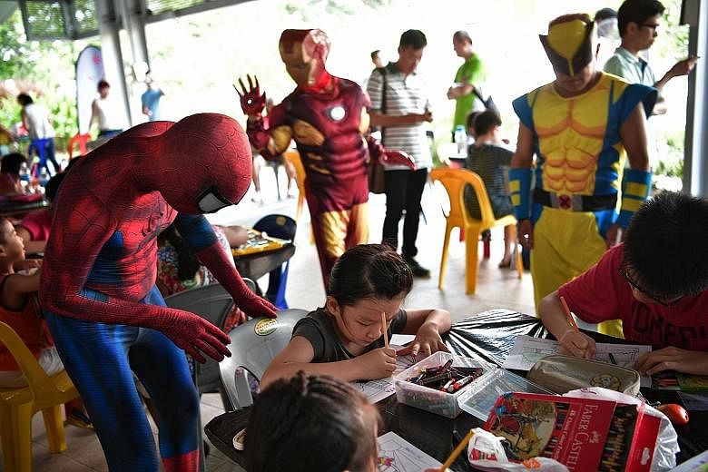 Mascots dressed as superheroes interacting with children taking part in a colouring competition during the launch of a temporary container library in Punggol West yesterday. The library in Punggol Walk, which was set up as the area's public library w
