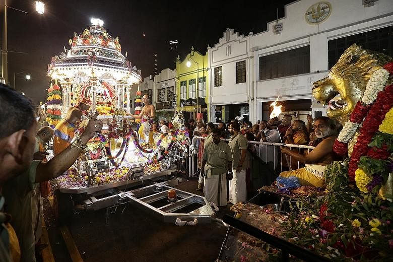 Devotees flanking a chariot as it arrives at the entrance of Singapore's oldest Hindu temple, the Sri Mariamman Temple in South Bridge Road, at around 1.05am yesterday. It had made its way to the temple in Chinatown from the Sri Srinivasa Perumal Tem