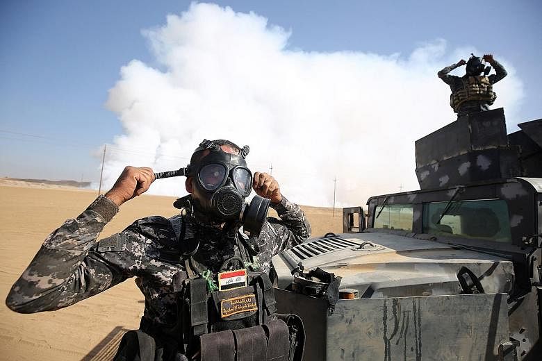 Iraqi forces wearing gas masks after fighters from the Islamic State in Iraq and Syria torched a sulphur factory about 30km south of Mosul on Saturday. The move was done in an effort to halt the offensive to recapture the city.