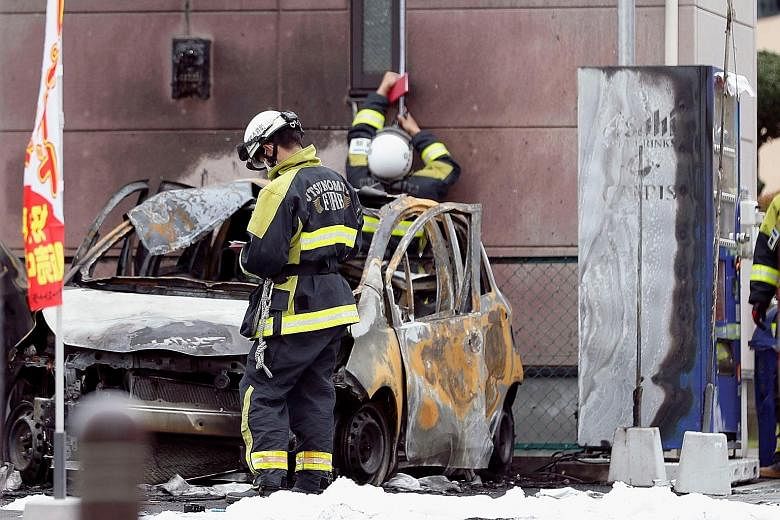 Firefighters investigating one of the burnt-out cars found after the explosions in Utsunomiya yesterday. A retired soldier killed himself in one of the explosions, which also injured two other men and a teenage boy.