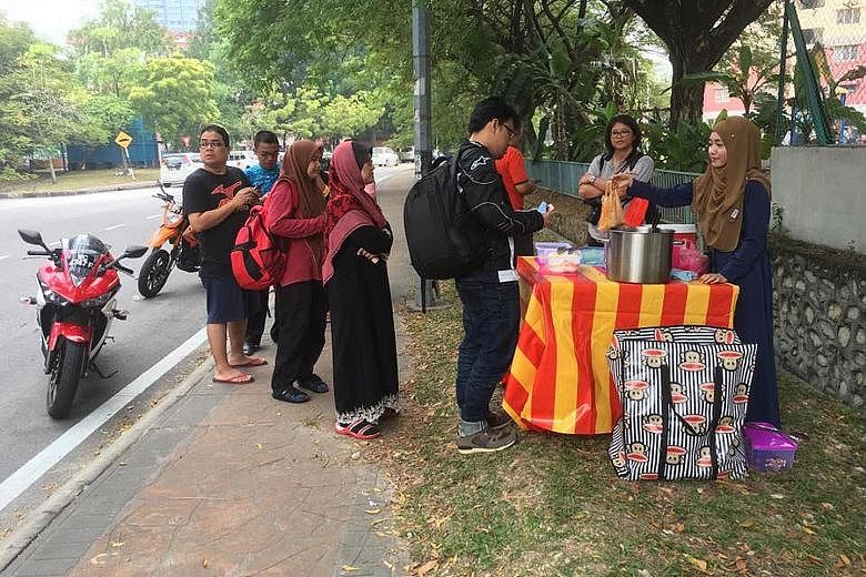 Electronic engineering graduate Siti Hajjar Ahmad (right) started selling her Nasi Lemak Anak Dara (Virgin Nasi Lemak) two months ago at the roadside in Selangor. She is waiting for her trader's licence to be approved by the Shah Alam Municipal Counc