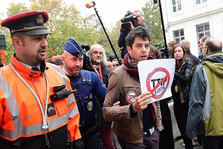 A demonstrator being led away by police ahead of the emergency meeting of Belgian federal entities in Brussels yesterday. The small Belgian region of Wallonia has set back the trade deal with Canada that all 27 other EU member states were ready to su