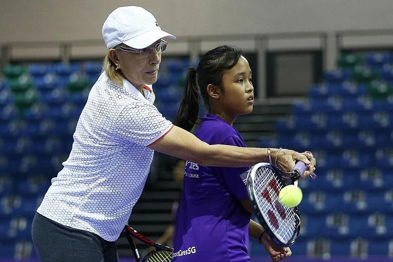 Retired tennis legend Martina Navratilova guides Naval Base Secondary School student Nur Nabila Malek, 13, on how to hit a forehand at a charity fund-raiser yesterday. Swiss doubles tennis player Martina Hingis was also present at the event, called "