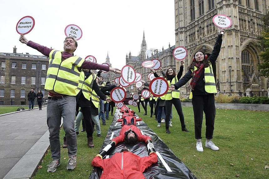 Protesters from Plane Stupid demonstrating outside the Houses of Parliament in London yesterday. According to a study, a new runway at Heathrow would create 70,000 jobs. However, residents are worried about demolition of several villages as well as a