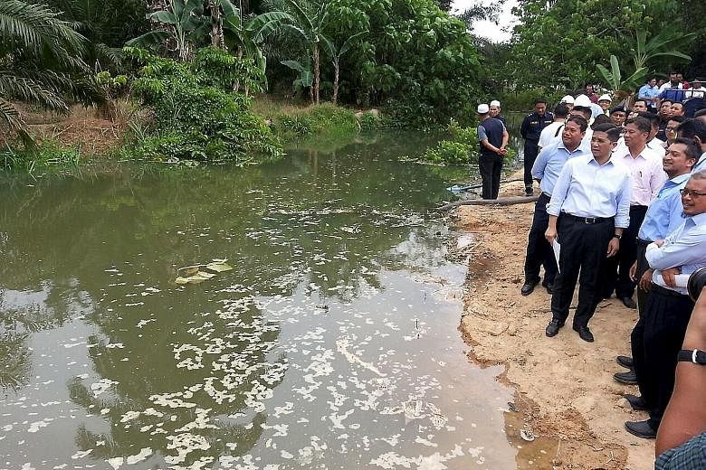 Selangor Menteri Besar Azmin (front row, third from right) in front of the contaminated Sungai Buah. A bund was built across the river to stop the water from flowing into Sungai Semenyih.