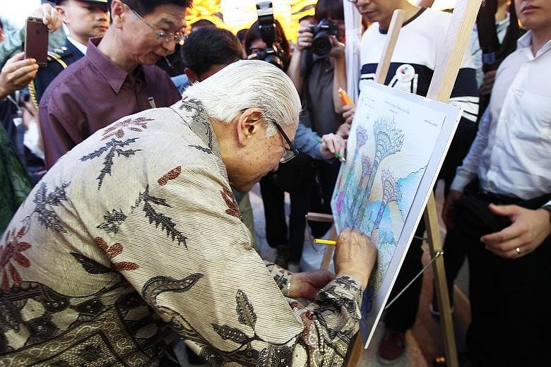 President Tony Tan Keng Yam putting the final touches to a colouring sheet featuring the Gardens by the Bay. The auction for the artwork will end on Saturday at 5pm.