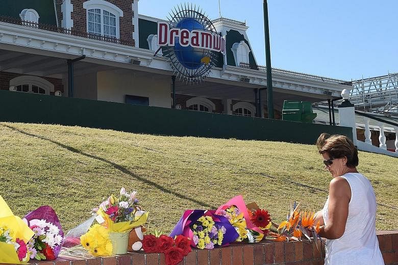 A woman laying flowers yesterday outside the Dreamworld theme park, which remains closed. A series of mechanical problems reportedly had plagued the water ride hours before the accident.
