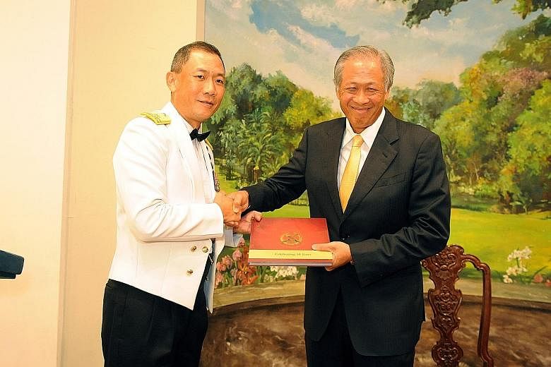 The institute's commandant, Rear-Admiral Giam Hock Koon (left), presenting the commemorative book to Dr Ng at the graduation ceremony yesterday.
